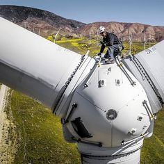 a man standing on top of a wind turbine