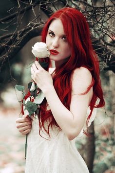 a woman with long red hair holding a rose