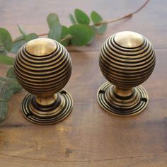 two metal candlesticks sitting on top of a wooden table