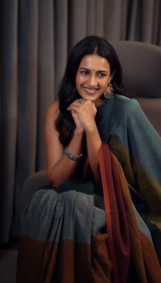 a woman sitting in a chair with her hand on her chin and smiling at the camera