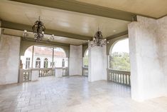 an empty room with two chandeliers and large windows overlooking the surrounding area is shown