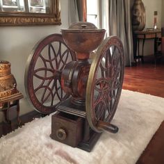 an old fashioned spinning machine sitting on top of a white rug