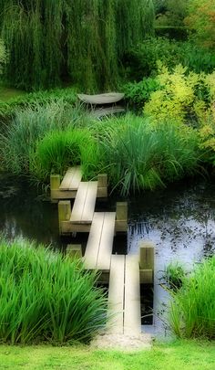 a wooden bridge over a small pond surrounded by green grass