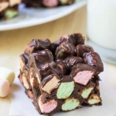 a close up of a piece of food on a plate with a glass of milk in the background