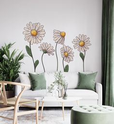 a living room with white couches and green pillows on the floor next to a large flower wall decal