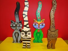 four cat figurines are lined up against a red wall