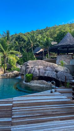 an outdoor swimming pool surrounded by palm trees and water features wooden steps leading up to it