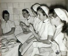 black and white photograph of nurses sitting at a table with food in front of them