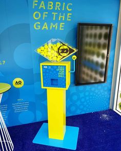 a yellow and blue stand with buttons on it in front of a sign that says fabric of the game