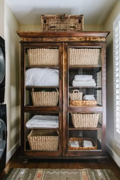 a wooden cabinet with baskets and towels in it