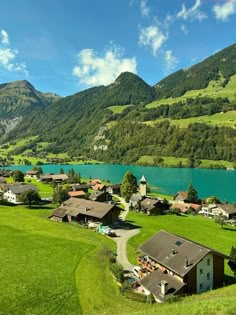 an aerial view of a small village near a lake in the middle of a mountain range