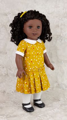 the doll is wearing a yellow dress with white polka dots on it and black shoes