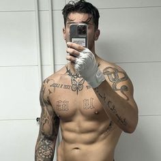 a shirtless man taking a selfie in front of a mirror with his cell phone