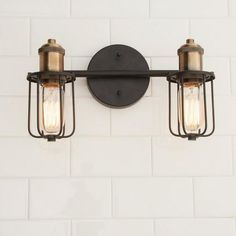 two light fixtures mounted on the wall in an industrial - style bathroom fixture with white tiles