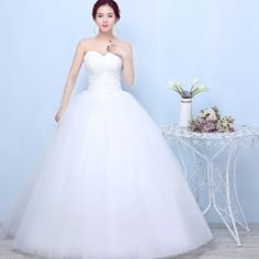 a woman in a white wedding dress standing next to a table with flowers on it