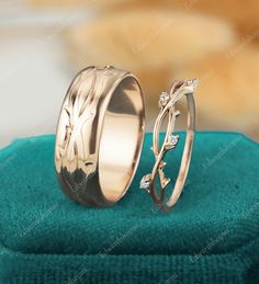 two wedding rings sitting on top of a blue towel next to each other with green stones