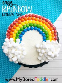 a rainbow cake with marshmallows on top and white frosting in the middle