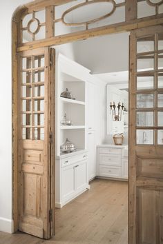 an open door leading into a kitchen with white cabinets and wood trim on the walls