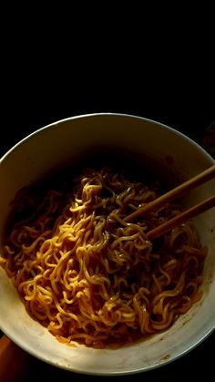 chopsticks in a bowl of noodles with sauce