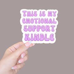 someone holding up a sticker that says, this is my emotionally support kindle