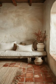 a white couch sitting on top of a brick floor next to a vase filled with flowers