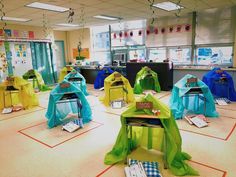 an empty classroom with many bags on the floor and tables covered in blue and green material