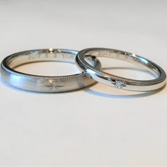 two silver wedding rings sitting on top of each other