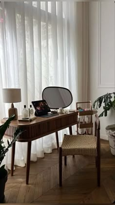 a desk with a mirror and chair in front of a window