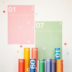 colorful rolls of paper sitting on top of each other in front of a wall calendar