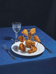 a white plate topped with food on top of a blue table cloth next to silverware