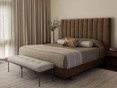 a bedroom with a bed, bench and window in the room that has curtains on both sides