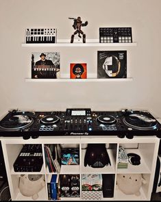 a dj's turntable in front of two shelves with records and cds on them