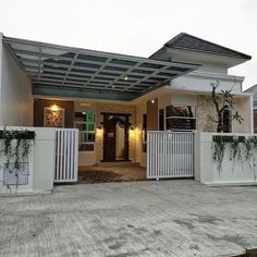 a house with a white fence and green plants on the front door, next to it