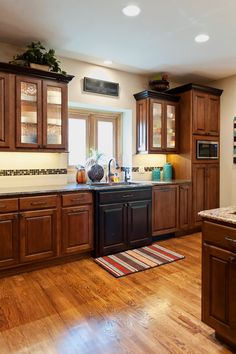 a kitchen with wooden floors and cabinets in the center, along with a rug on the floor