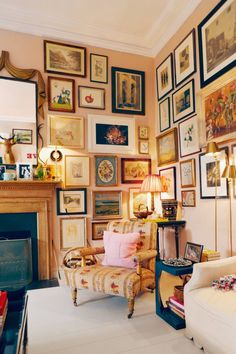 a living room filled with lots of framed pictures on the wall above a fire place