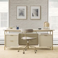 an office desk with two pictures on the wall above it and a chair in front of it