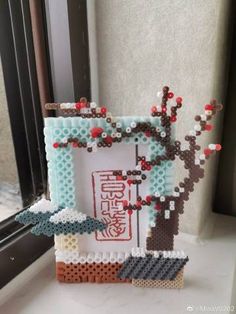 a photo frame made out of legos on a window sill next to a tree