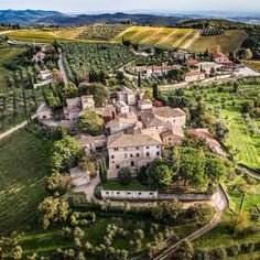 an aerial view of a village surrounded by green fields and olive trees in the countryside