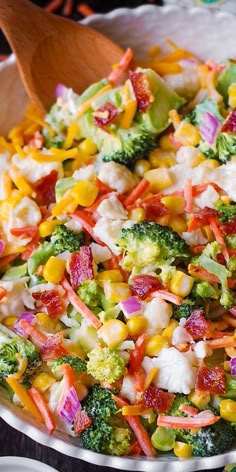 a colorful salad with broccoli, corn and carrots in a white bowl