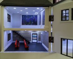 the inside of a dollhouse with two red chairs and a fish tank in it