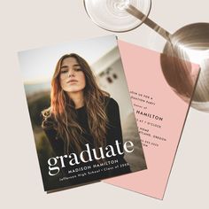 a wine glass next to a graduation card on top of a pink and white background