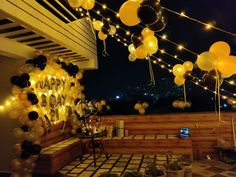 balloons and streamers are strung from the ceiling above a patio area at night time