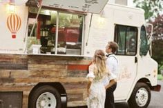 a man and woman standing in front of a food truck