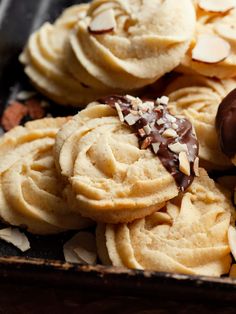 several cookies with chocolate and almonds are in a box on the table, ready to be eaten