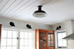 a kitchen with wooden cabinets and black lights above the stove top, along with white tile flooring