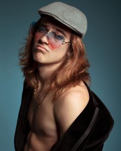 a shirtless man with long red hair wearing a hat and eye patch on his face