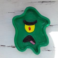 a green object with a hat on it's head and eyes painted on the side