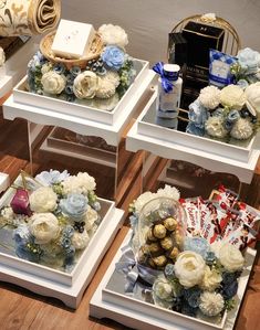 three white tables with flowers and gifts on them