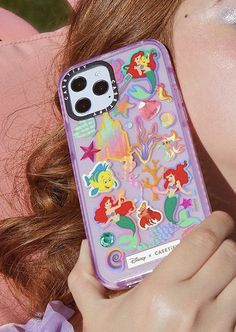 a girl holding up her phone case with little mermaid stickers on it