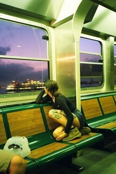 a woman sitting on a train seat with her head in her hands while looking out the window